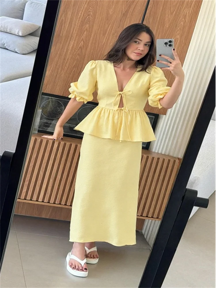 Woman taking a mirror selfie wearing a yellow dress in a living room.