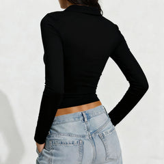 Person wearing a black long-sleeve crop top and light blue jeans on a white background