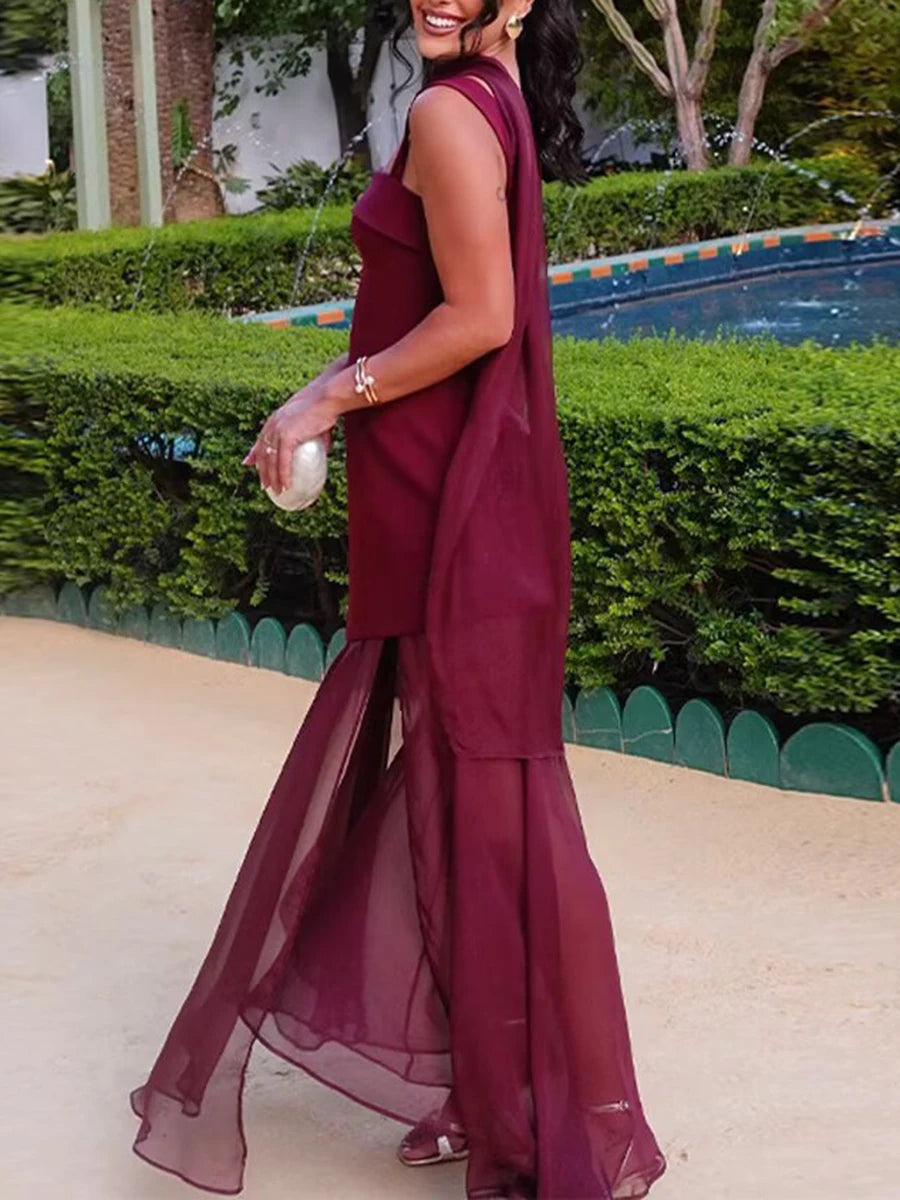 Woman in a burgundy dress standing outdoors with greenery in the background