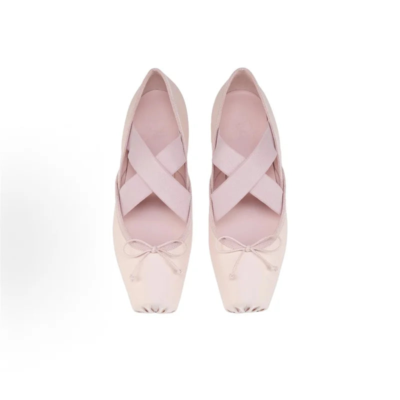 Pair of pink ballet shoes with ribbons on a white background
