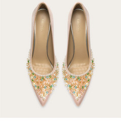 Pair of embellished pink high heels on a light beige background