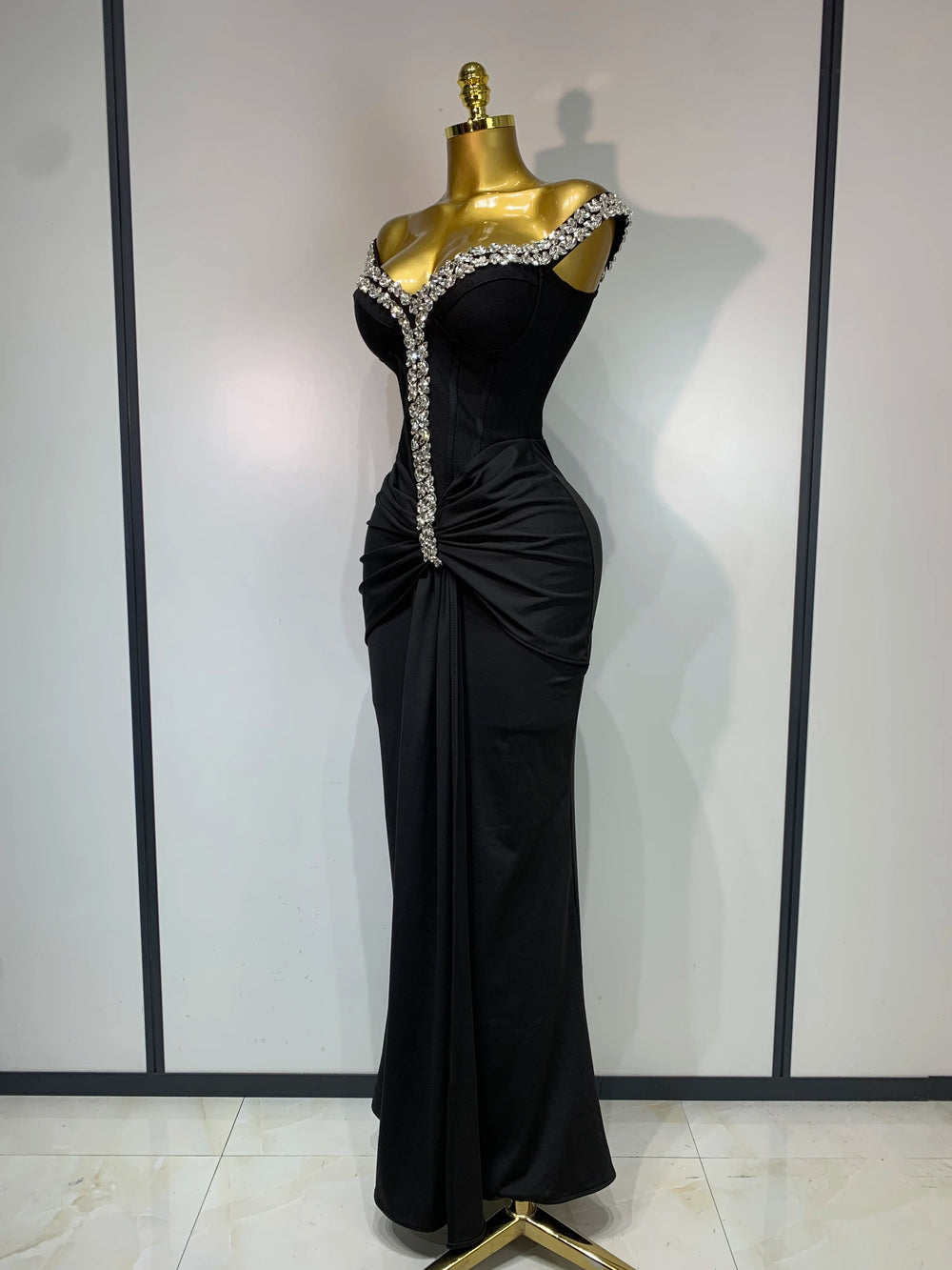 Side view of an off-the-shoulder draped bandage dress with diamond embellishments