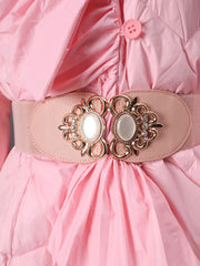 Close-up of a pink dress with a decorative belt featuring gold and pearl-like embellishments.