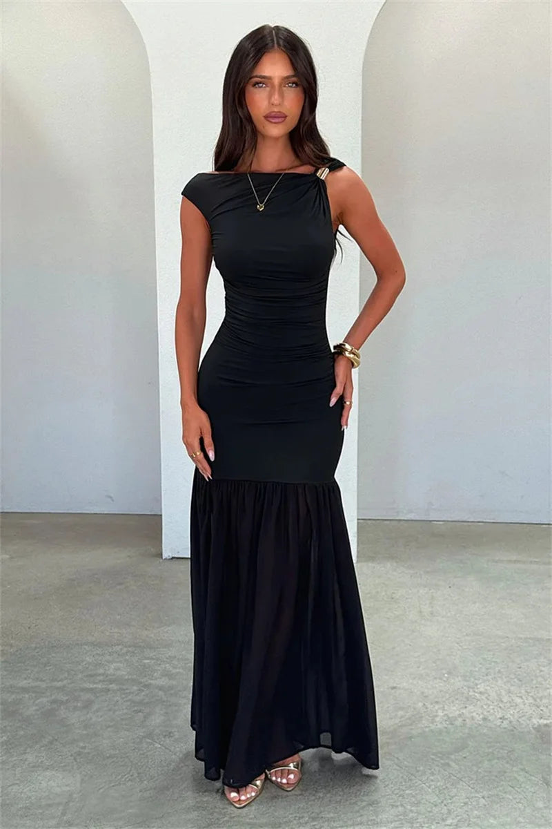 Woman wearing a black dress standing against a white wall.