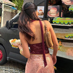 Woman in a pink dress eating a burger in front of a food truck.