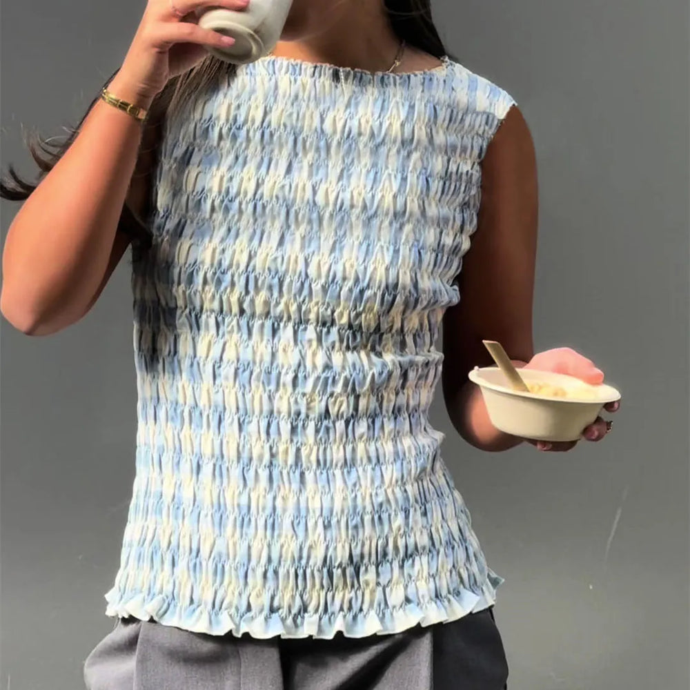 Person wearing a blue and white patterned sleeveless top holding a cup and a bowl.