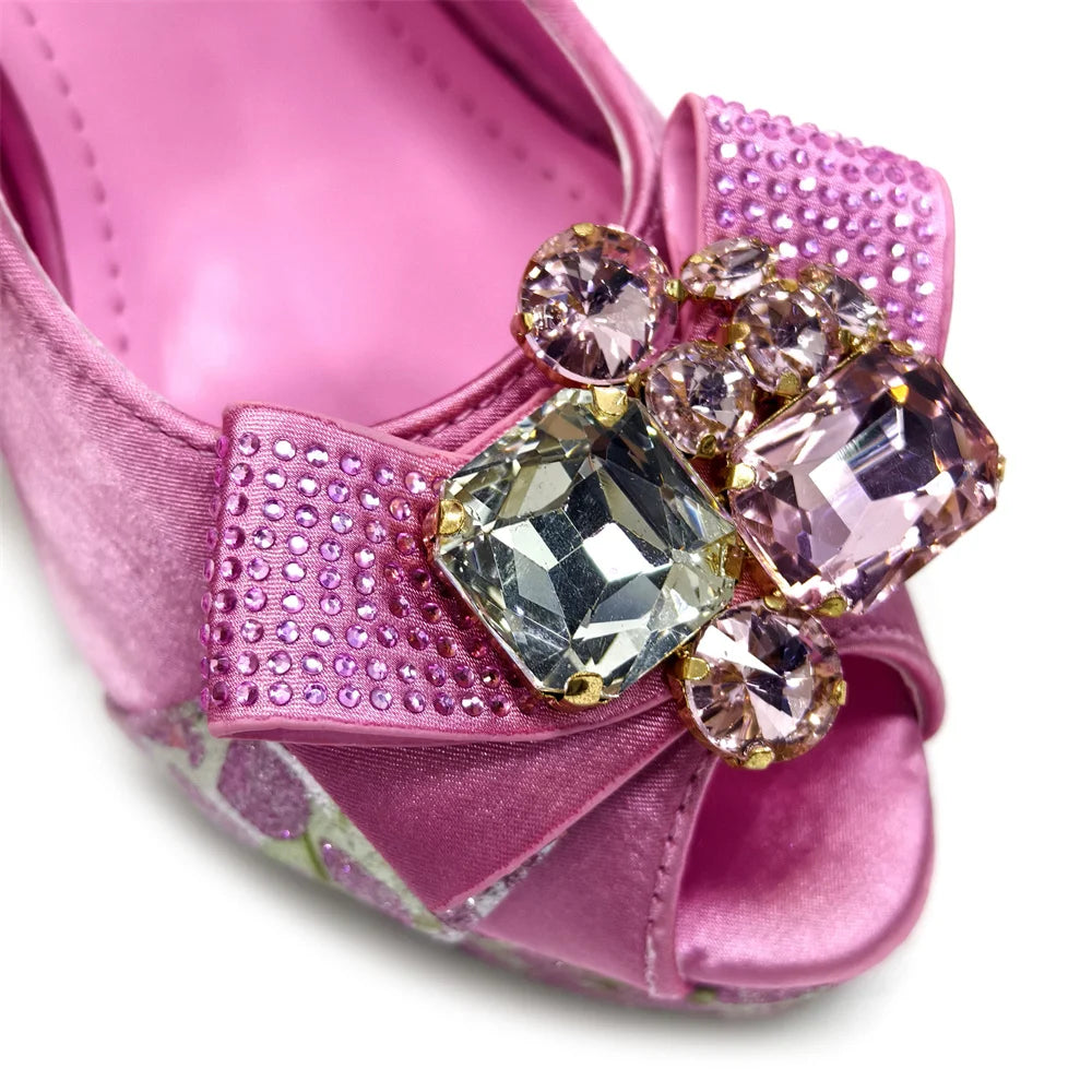 Pink high-heeled shoe with a decorative bow and crystals on a white background