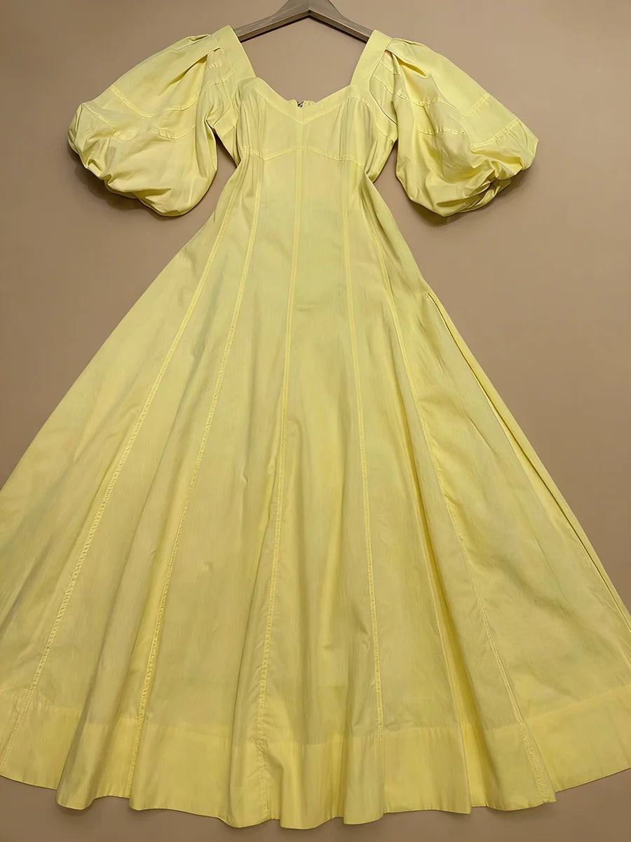 Yellow dress with puffed sleeves on a hanger against a brown background