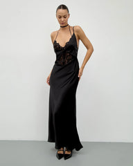 Woman wearing a black satin evening gown with lace details against a white background