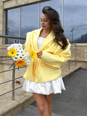 Woman in a yellow blazer holding flowers outdoors