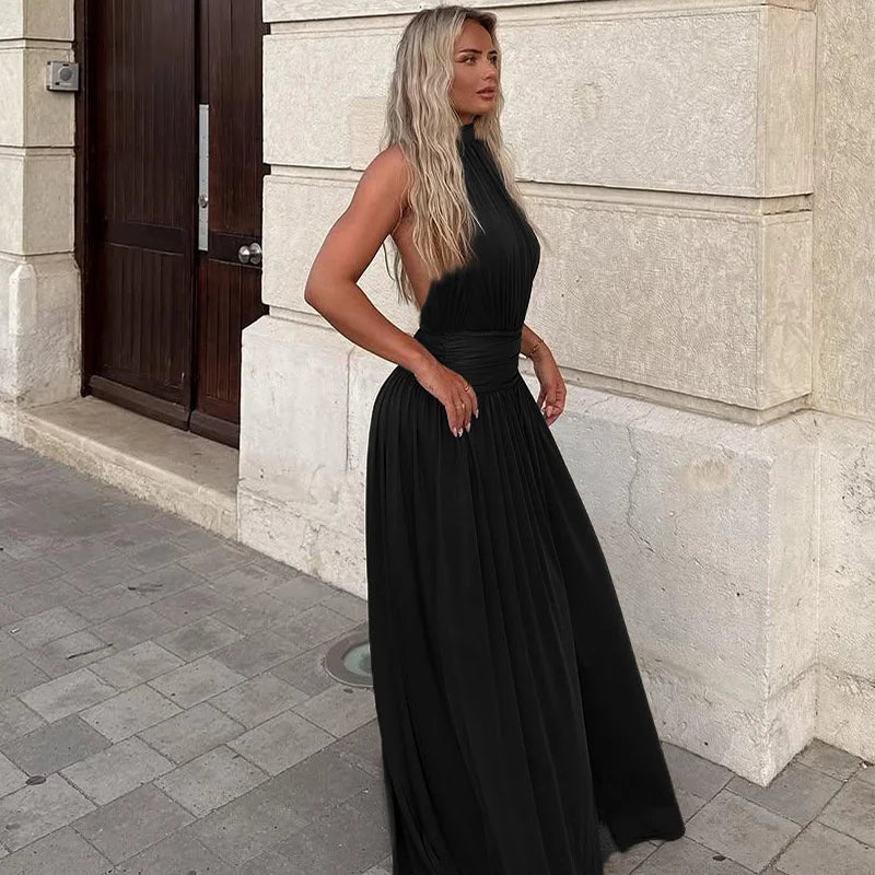 Woman in a black dress standing against a stone building.