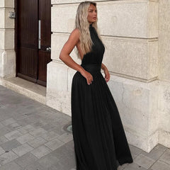 Woman in a black dress standing against a stone building.