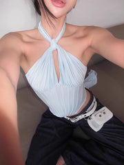 Person wearing a light blue halter top and dark pants with a white strap.