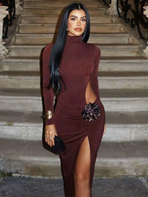 Woman in a burgundy dress with a high slit standing on stone steps.