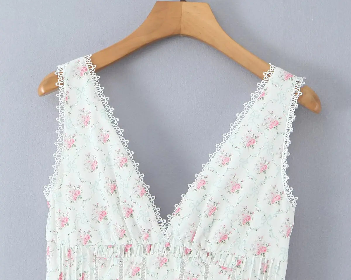 White lace top with pink floral patterns on a wooden hanger against a gray background