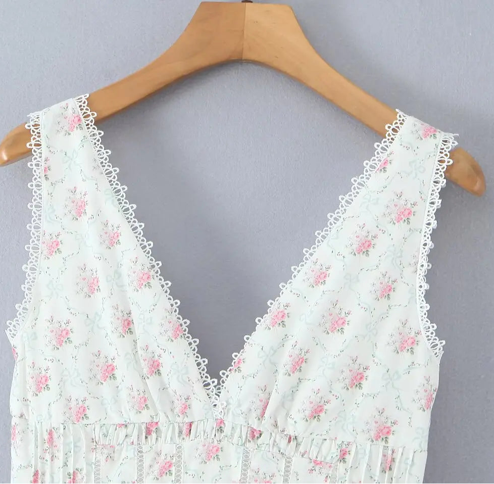 White lace top with pink floral patterns on a wooden hanger against a gray background