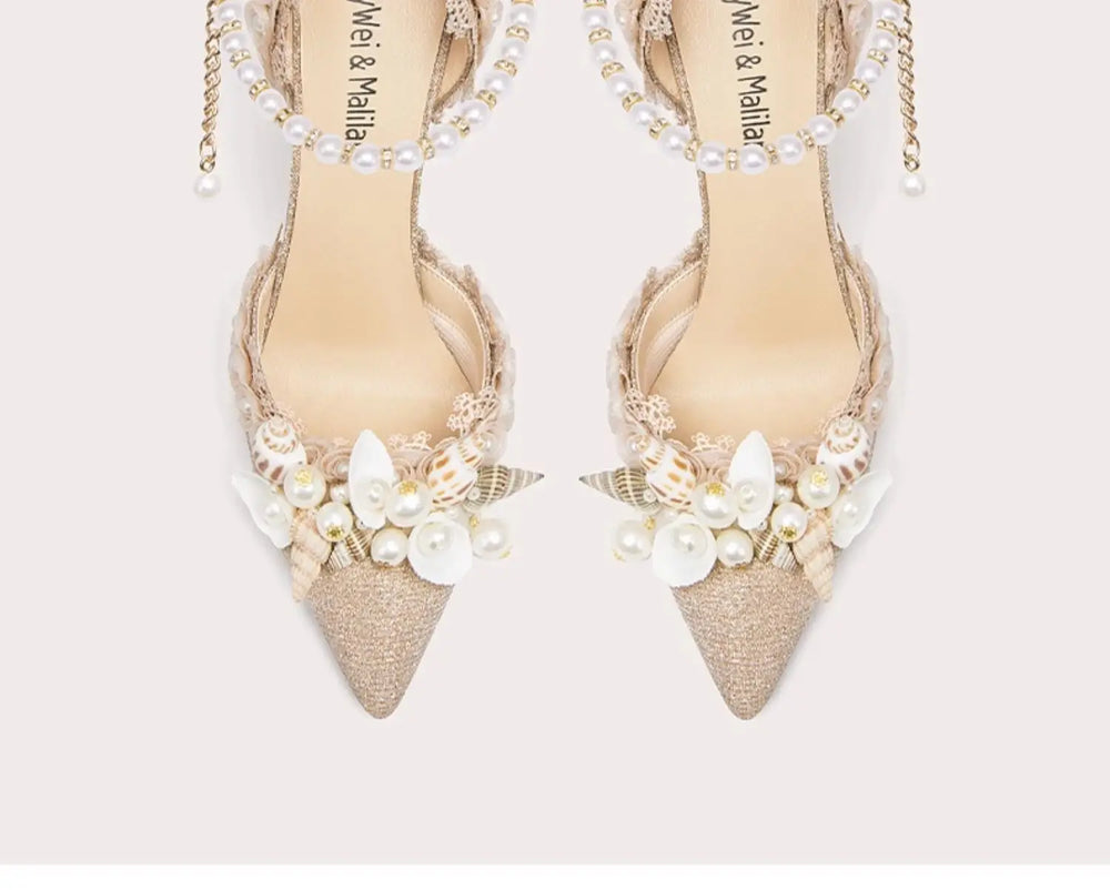 Pair of beige pointed-toe shoes with pearl embellishments on a light background
