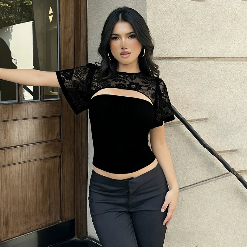 Woman wearing a black lace top and dark pants standing outdoors.