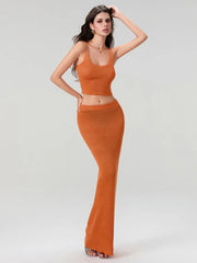 Woman wearing an orange knit outfit on a plain background