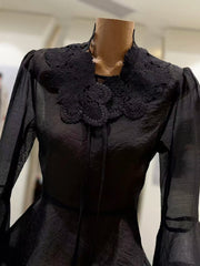 Black dress with intricate lace collar on a mannequin against a neutral background