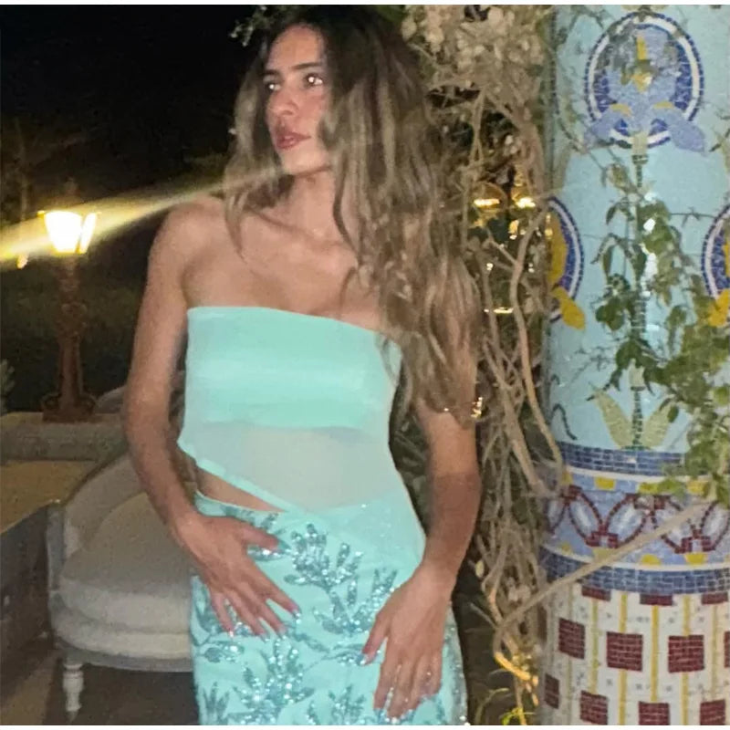 Woman in a light blue dress standing outdoors with decorative elements in the background