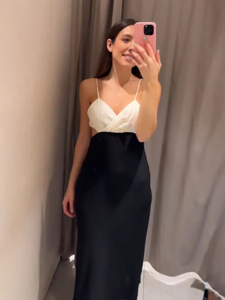 Woman taking a mirror selfie wearing a white top and black skirt against a plain background