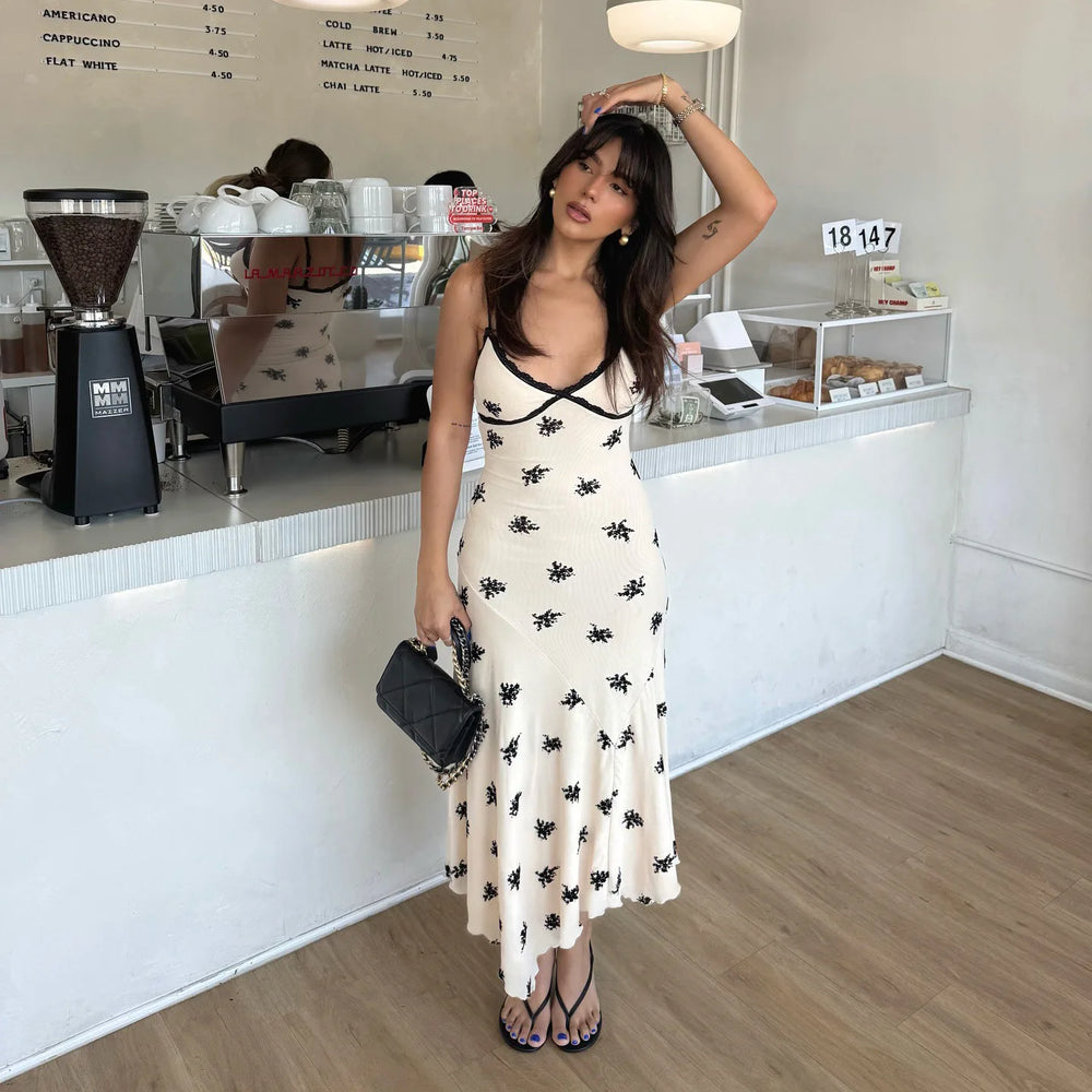 Woman in a white dress with black patterns standing in a coffee shop.