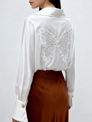 White blouse with butterfly design on the back worn by a person against a white background