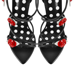 Close-up of the toe area of black lace-up stiletto heeled sandals with rose and polka dot details.