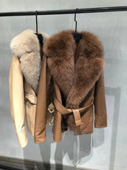 Two leather jackets with fur collars on a rack against a gray background