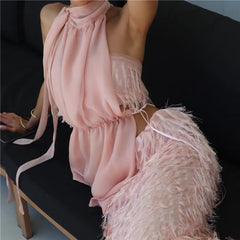 Person wearing a pink fringe dress sitting on a black chair.