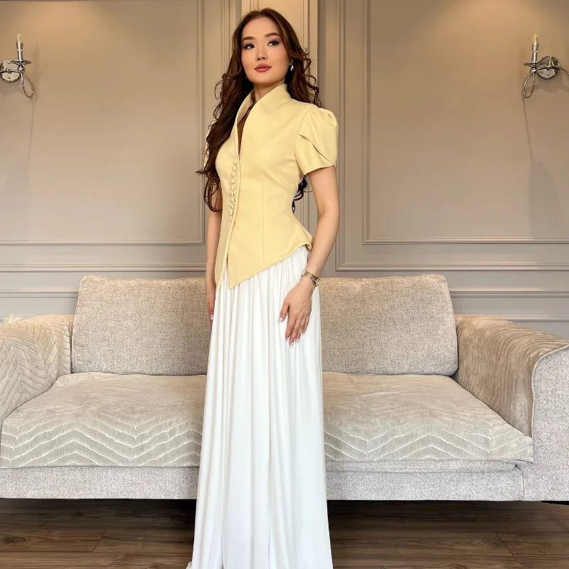 Woman in a yellow top and white skirt standing in a room with a gray sofa.