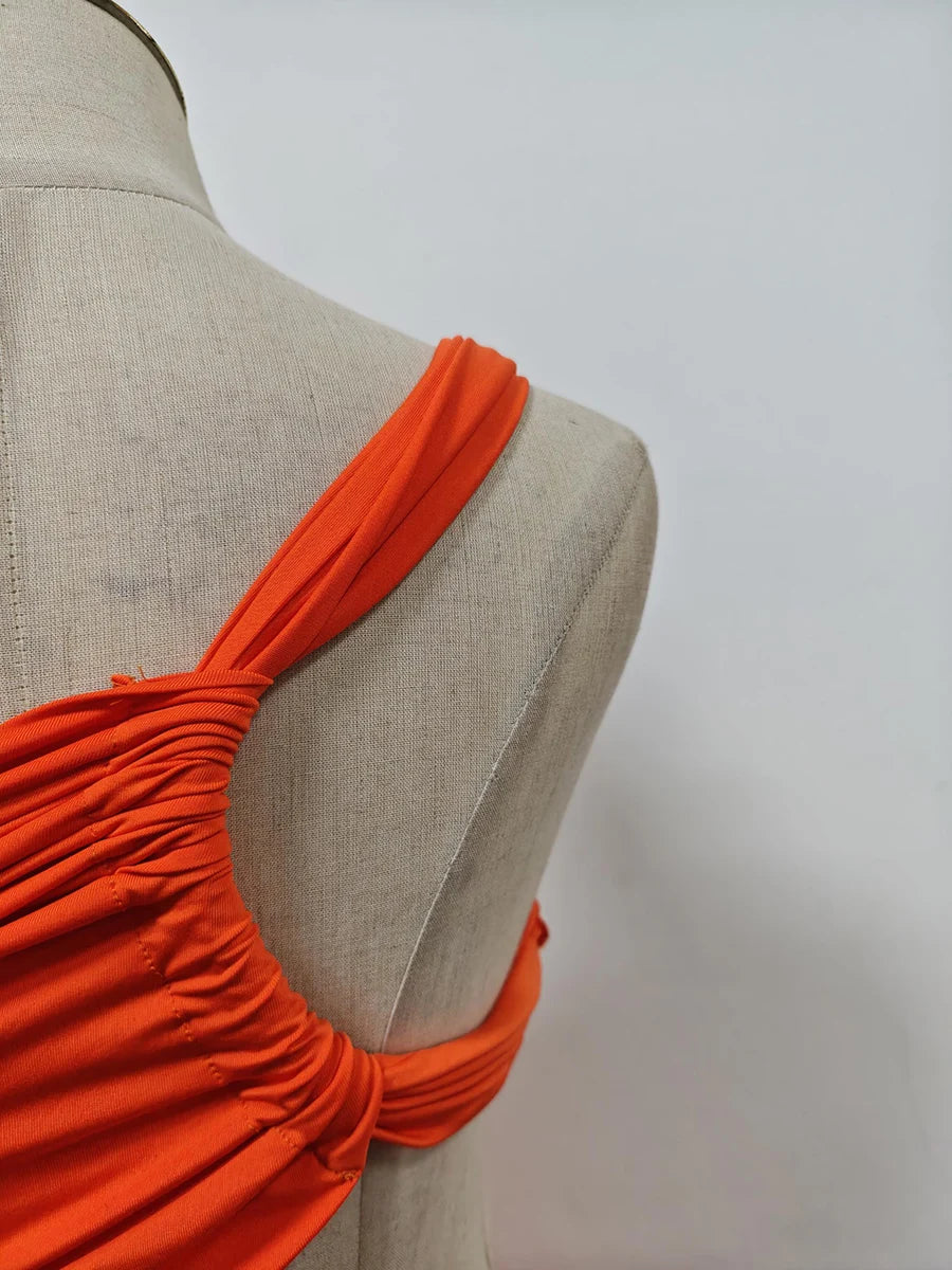 Orange dress on a mannequin against a plain background