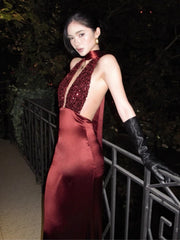 Woman in a red evening gown with a deep neckline and black gloves standing outdoors at night.