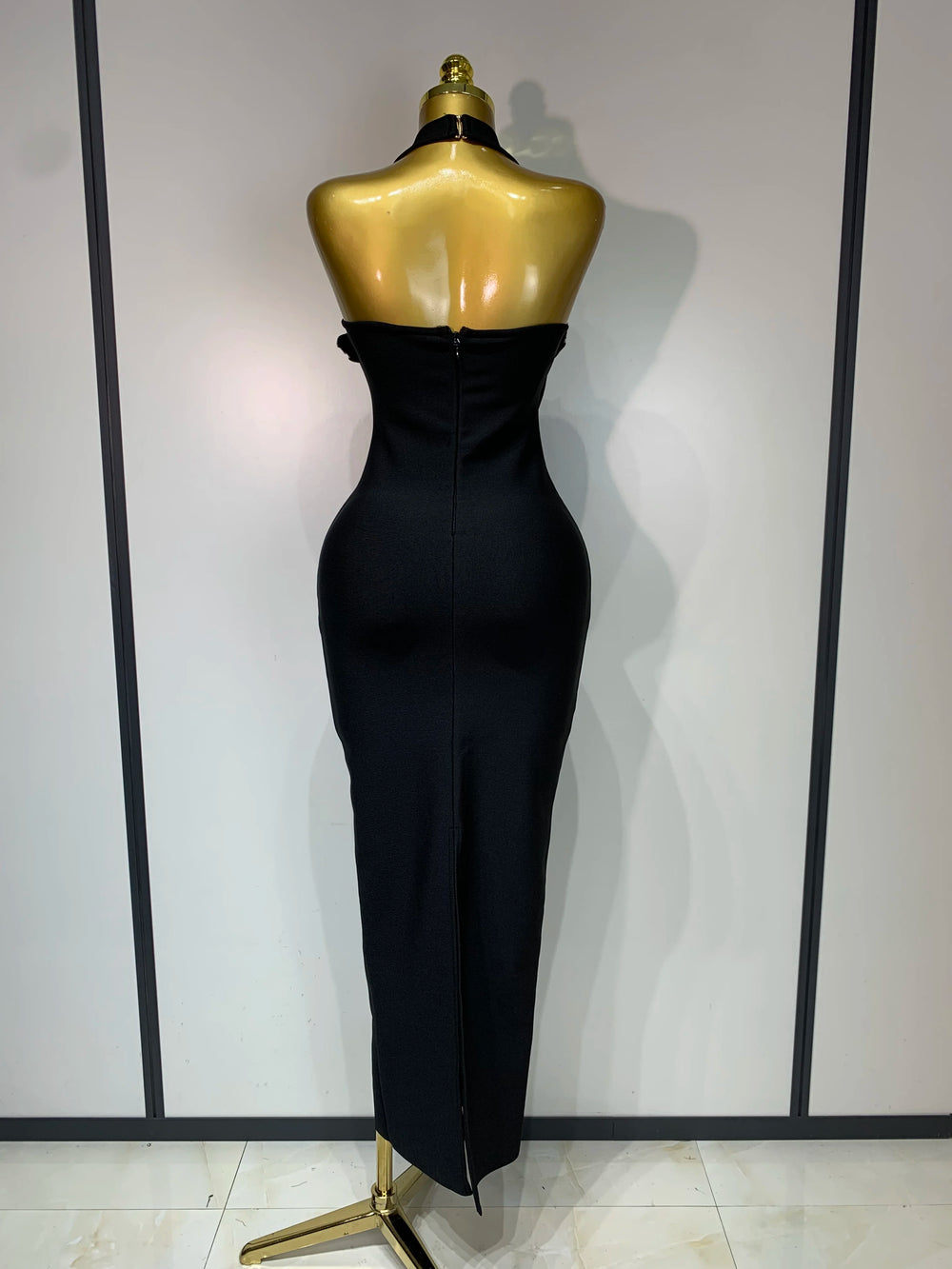 Black evening gown with a large bow on a mannequin against a white wall.