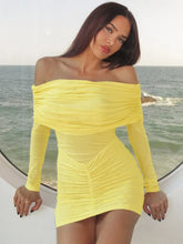 Woman wearing a yellow off-shoulder dress by the ocean.