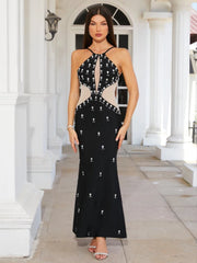 Woman wearing a black evening gown with silver embellishments in front of classical architecture.