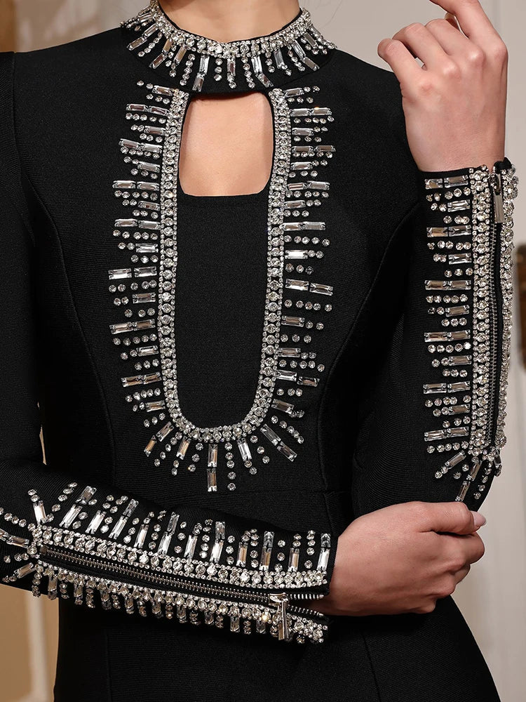 Black outfit with silver embellishments held by a hand against a neutral background