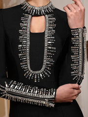 Black outfit with silver embellishments held by a hand against a neutral background