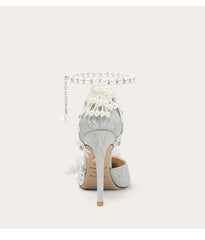 Silver high-heeled shoe with decorative elements on a white background