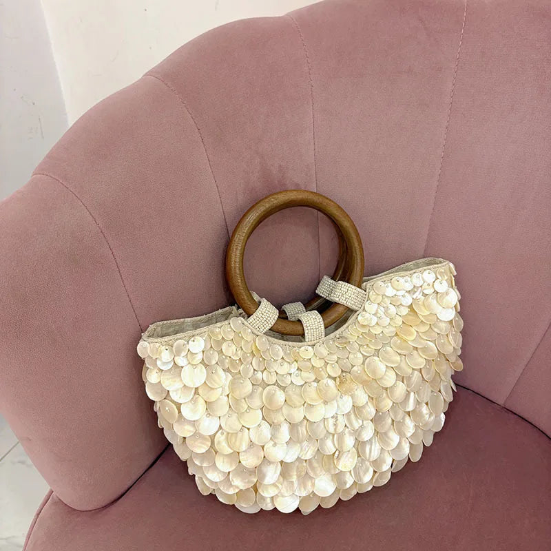 Sequined handbag with wooden handle on a pink cushion