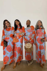 Four women wearing matching floral dresses posing against a white wall.