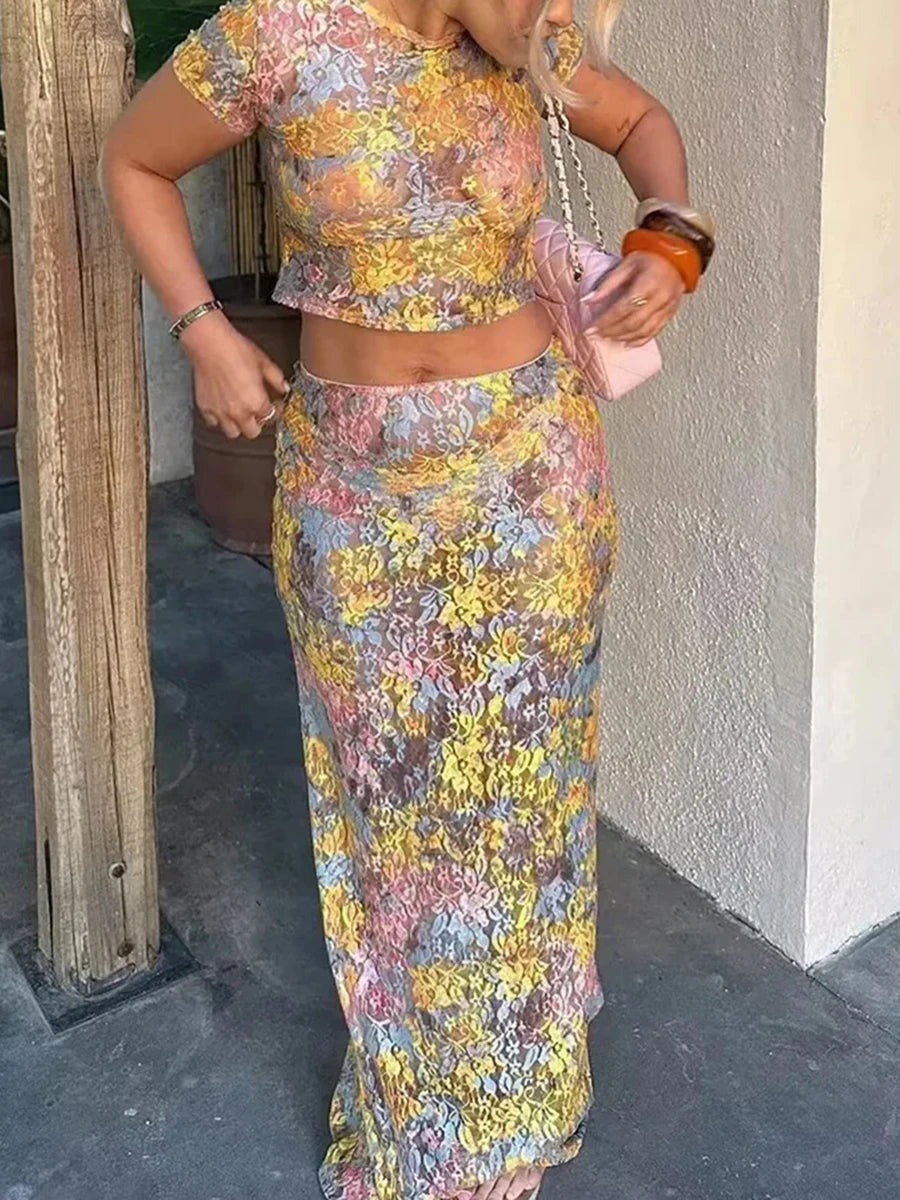 Person wearing a colorful floral outfit standing against a neutral wall.