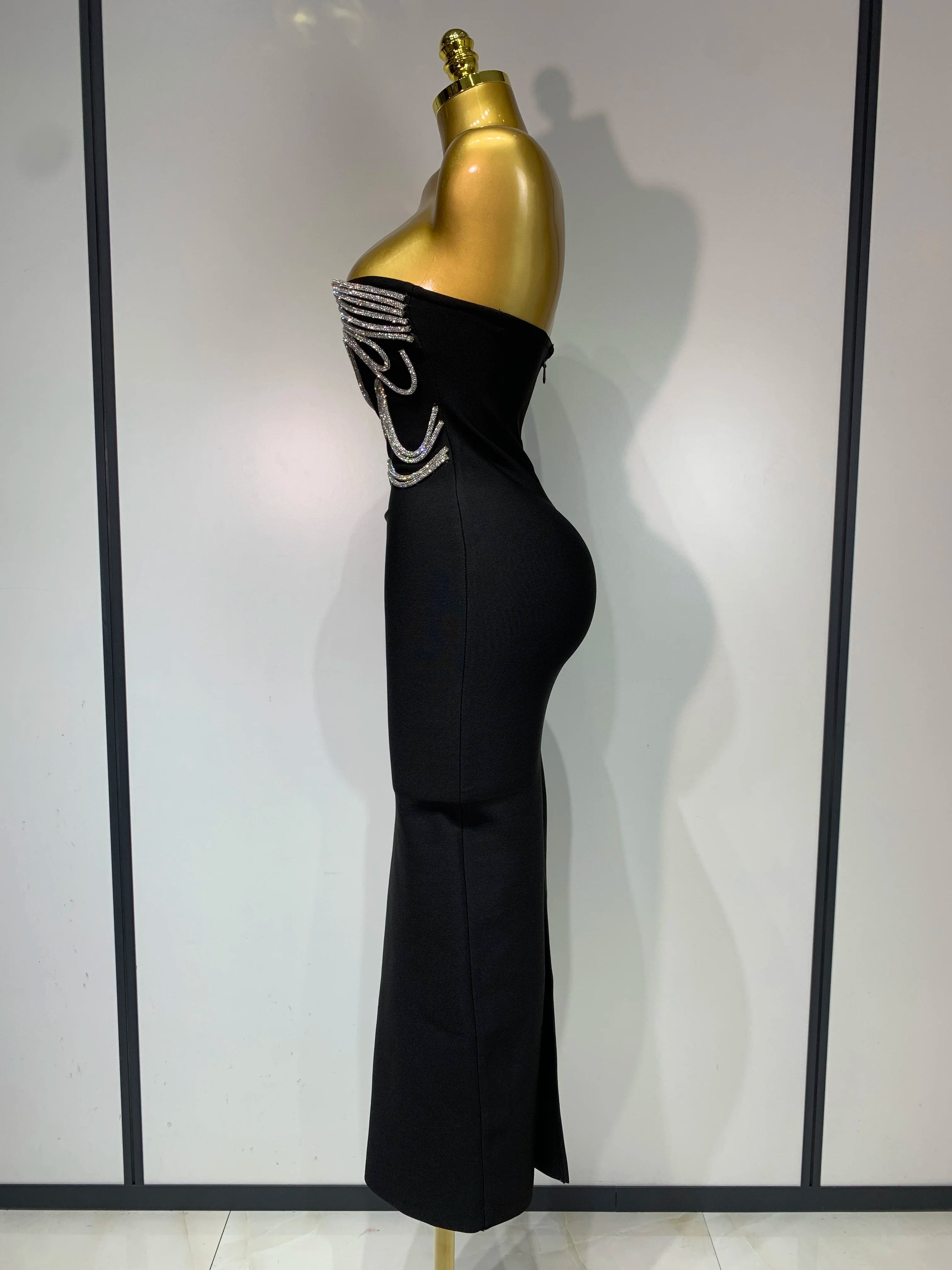 Black evening gown with gold embellishments on a mannequin against a white background