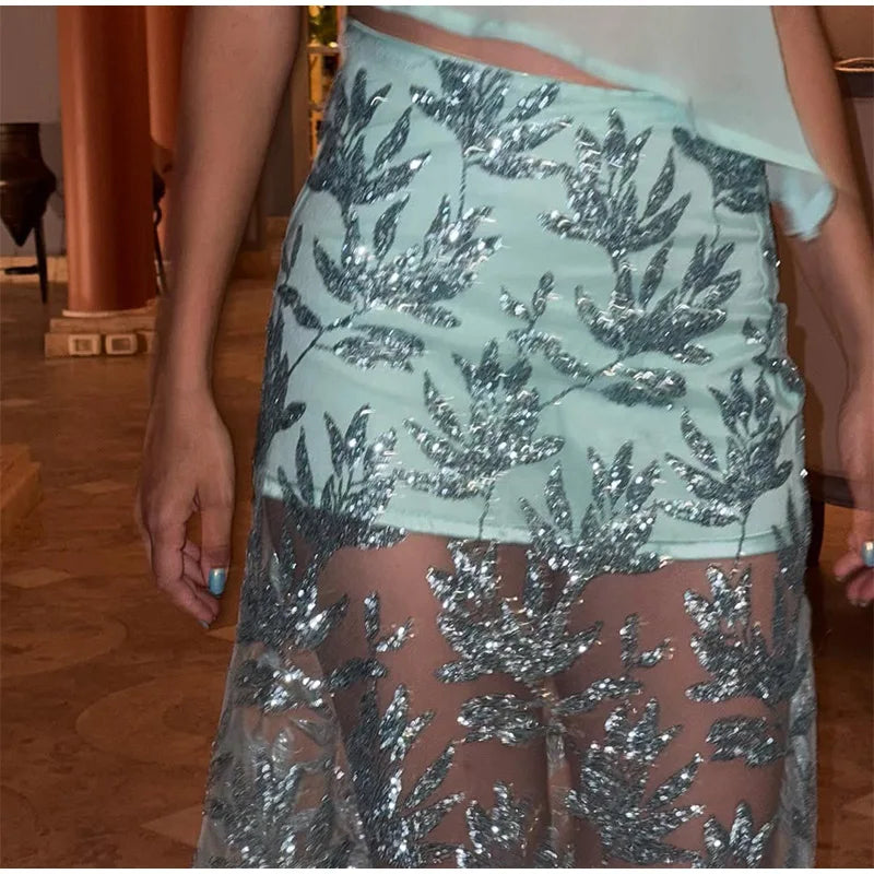 Close-up of a person wearing a light blue sequin skirt with a floral pattern.