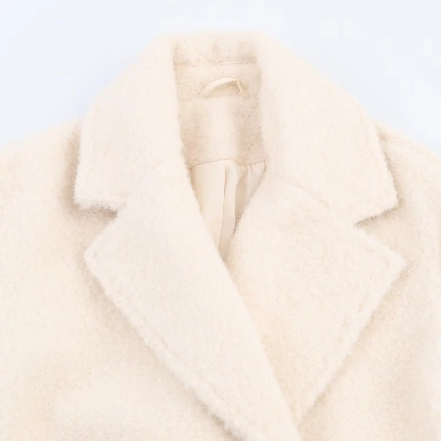 Close-up of a cream-colored coat on a light gray background