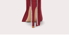 Red high-heeled shoe with studded details on a light gray background