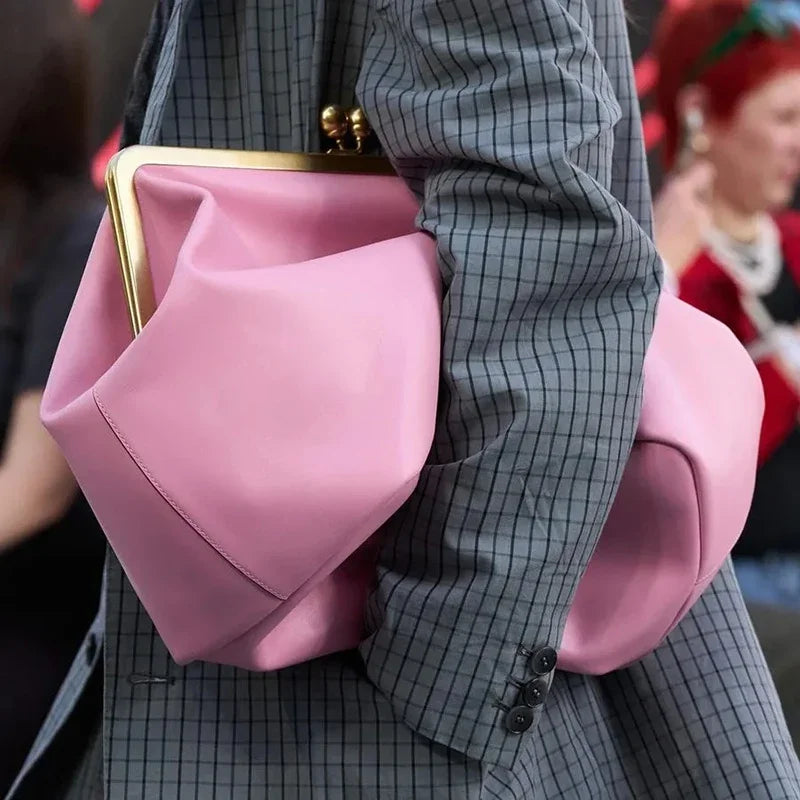 Person wearing a gray checkered suit with a pink bag over one shoulder.