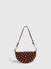 Maroon handbag with gold studs on a light gray background