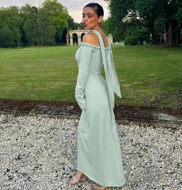 Woman in a light green dress standing on a gravel path with trees and grass in the background